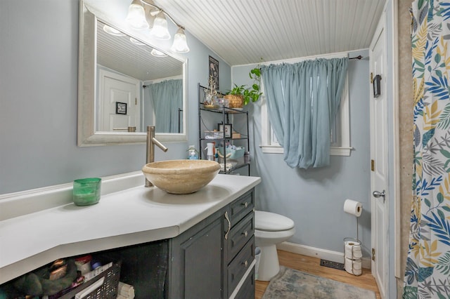 full bath with toilet, vanity, baseboards, and wood finished floors