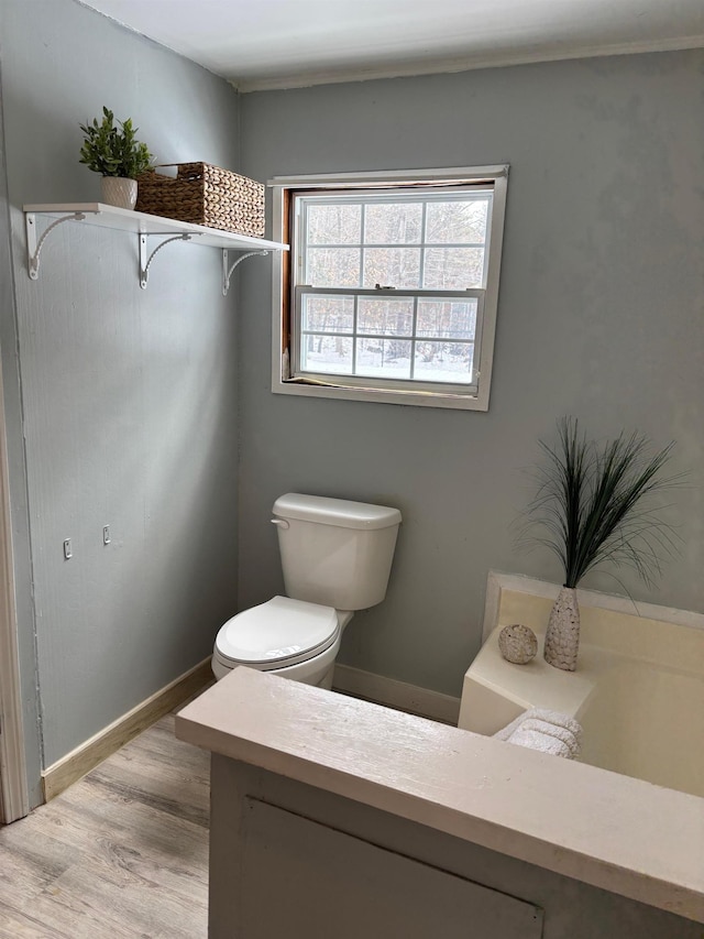 bathroom featuring toilet, wood finished floors, and baseboards