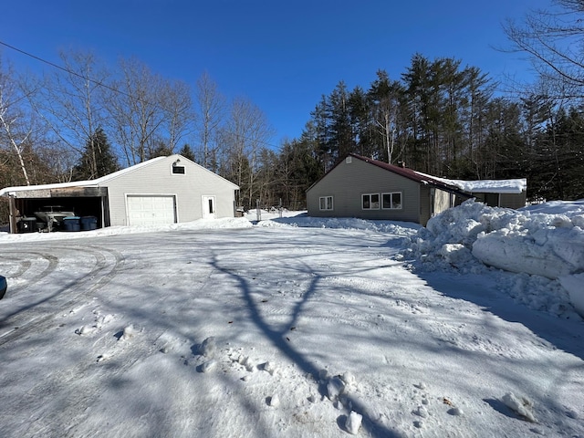 yard layered in snow with an outbuilding and a garage