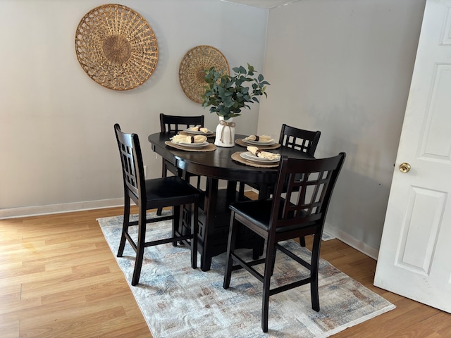 dining area with baseboards and light wood finished floors