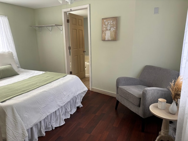 bedroom with ensuite bathroom, baseboards, and wood finished floors