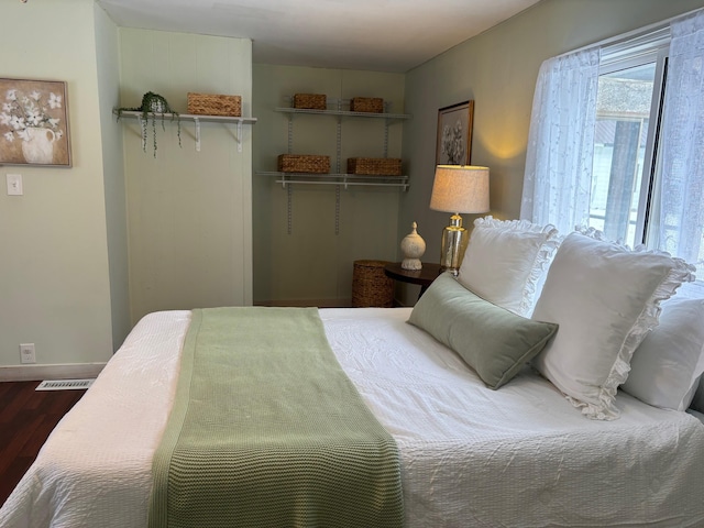 bedroom with a closet, baseboards, dark wood-type flooring, and visible vents