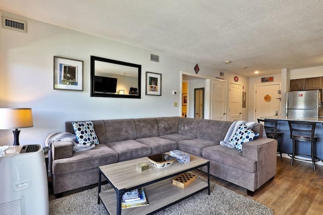 living area featuring wood finished floors, visible vents, and a textured ceiling