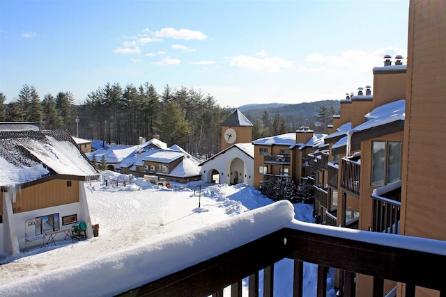 snow covered back of property featuring a residential view and a mountain view