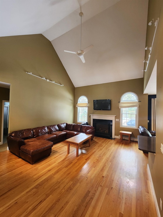 living room with a fireplace with flush hearth, a healthy amount of sunlight, ceiling fan, and wood finished floors