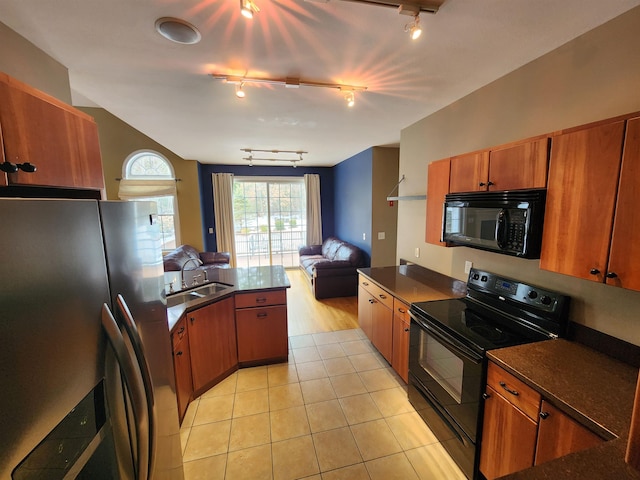 kitchen with brown cabinets, black appliances, open floor plan, a peninsula, and light tile patterned floors