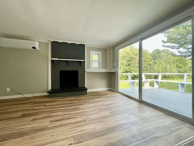 unfurnished living room with an AC wall unit, a brick fireplace, baseboards, and light wood finished floors