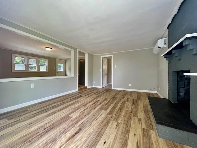 unfurnished living room featuring a fireplace, a wall unit AC, wood finished floors, and baseboards