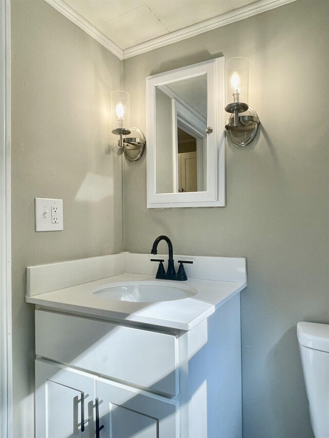 bathroom featuring toilet, vanity, and ornamental molding