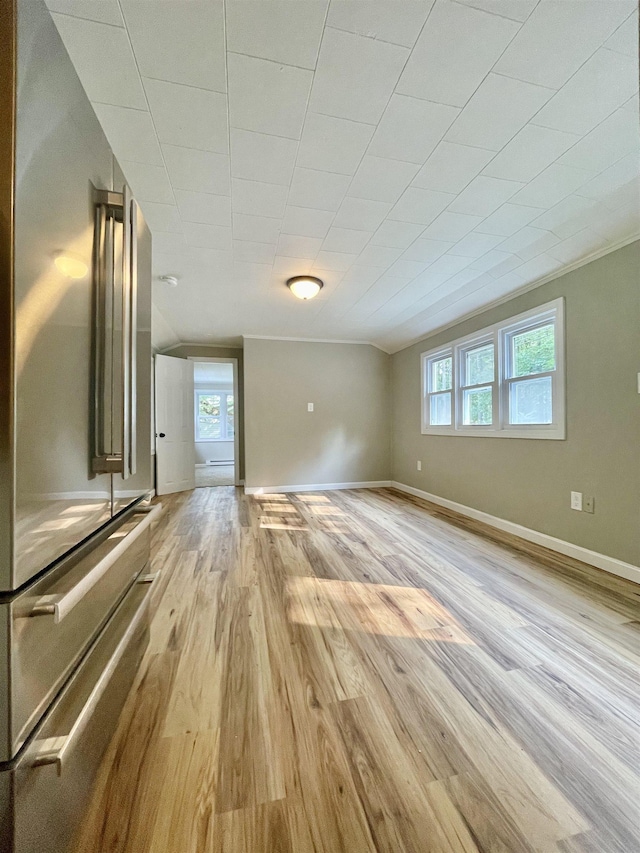unfurnished living room featuring a wealth of natural light, light wood-type flooring, and baseboards