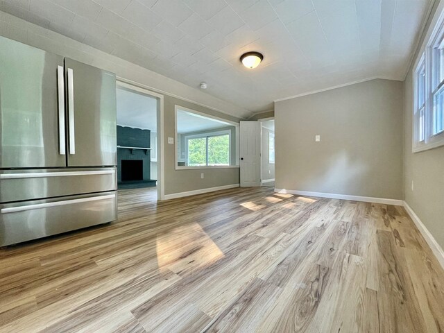 unfurnished living room with light wood finished floors, plenty of natural light, and baseboards