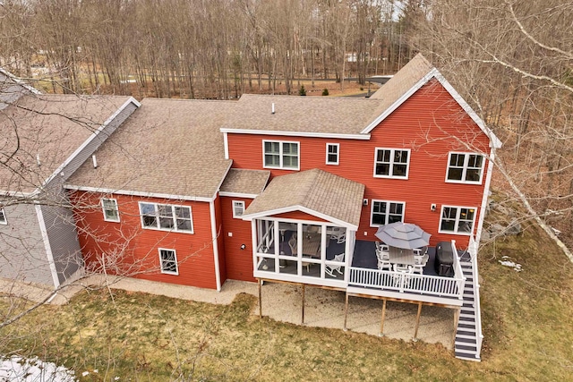 back of property with a sunroom and roof with shingles