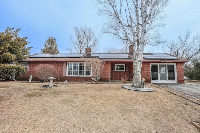 rear view of property featuring brick siding, a chimney, and a yard