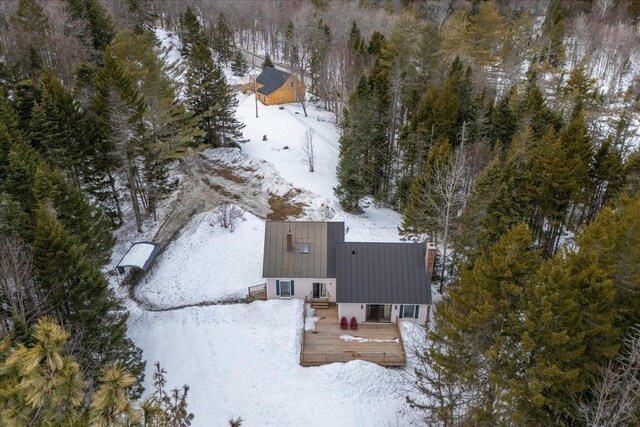 snowy aerial view with a wooded view
