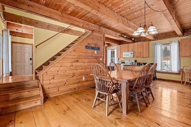 dining space with light wood finished floors, stairway, beamed ceiling, and an inviting chandelier