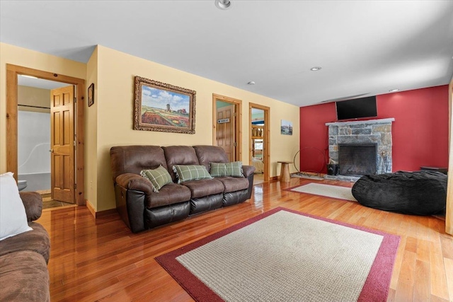 living room with a fireplace, recessed lighting, wood finished floors, and baseboards
