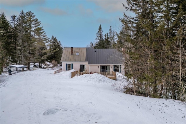 snow covered rear of property featuring metal roof and a standing seam roof