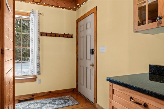 doorway to outside with light wood finished floors, visible vents, and baseboards