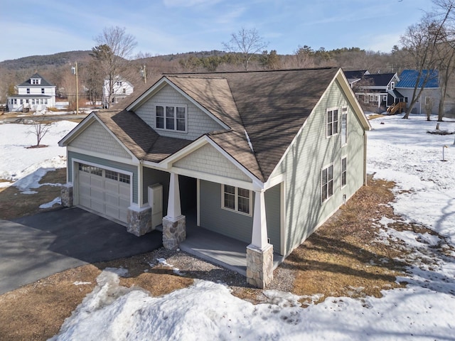 view of front facade with aphalt driveway, roof with shingles, covered porch, and an attached garage