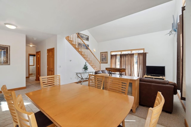 dining room featuring light tile patterned floors, stairs, baseboards, and vaulted ceiling