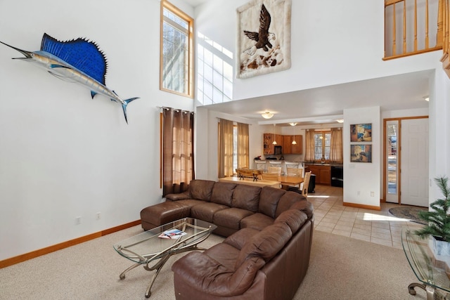 living area featuring light tile patterned floors, light colored carpet, baseboards, and a high ceiling