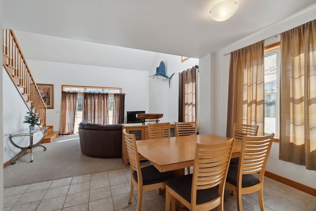 dining room with light tile patterned floors, light carpet, a healthy amount of sunlight, and stairs