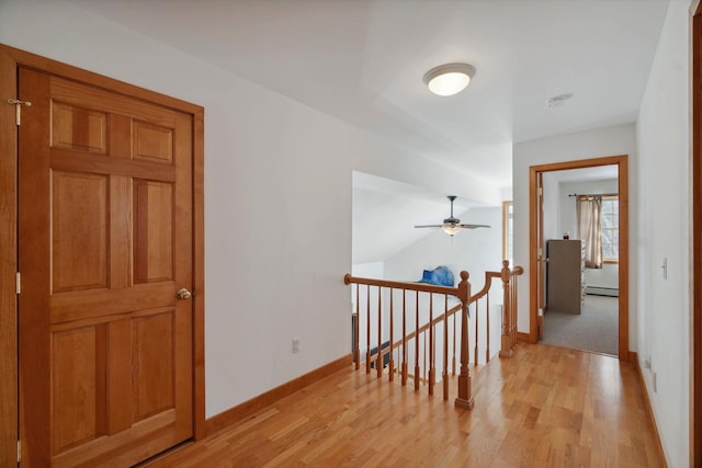 corridor featuring baseboards, an upstairs landing, light wood-style flooring, and a baseboard radiator