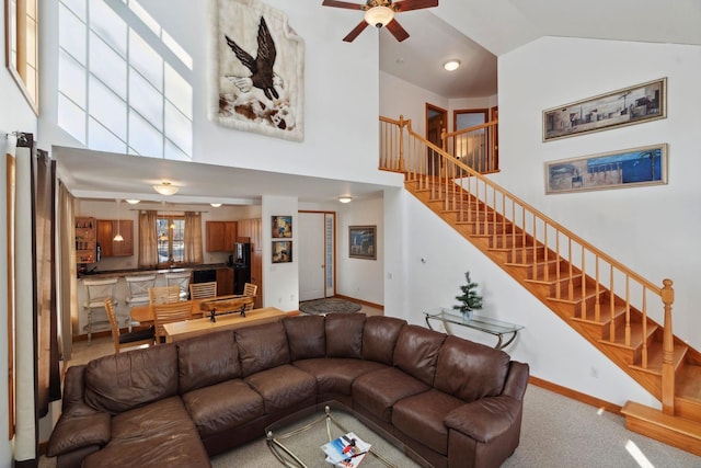 living room featuring high vaulted ceiling, stairway, carpet flooring, baseboards, and ceiling fan