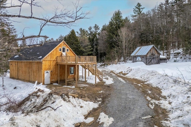 snow covered structure featuring an outdoor structure, stairway, and a barn