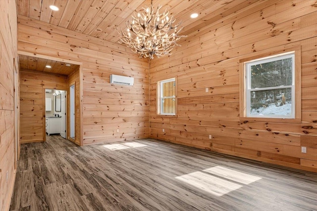 spare room featuring wooden walls, wood ceiling, an AC wall unit, an inviting chandelier, and wood finished floors