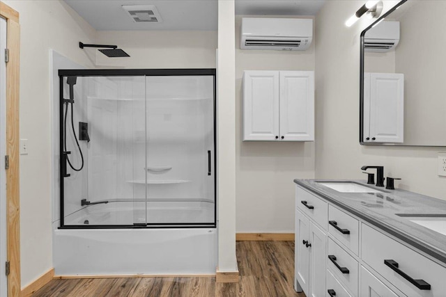 bathroom with wood finished floors, combined bath / shower with glass door, an AC wall unit, and a sink