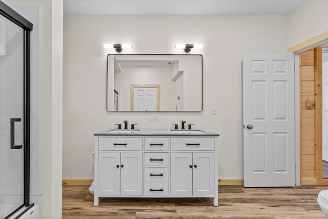 bathroom with double vanity, wood finished floors, and a sink