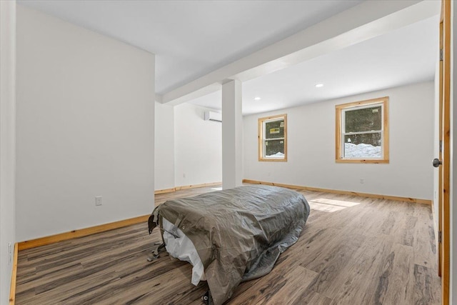bedroom featuring a wall mounted air conditioner, baseboards, and wood finished floors