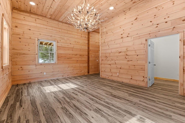 unfurnished room with wood walls, recessed lighting, wooden ceiling, wood finished floors, and a notable chandelier