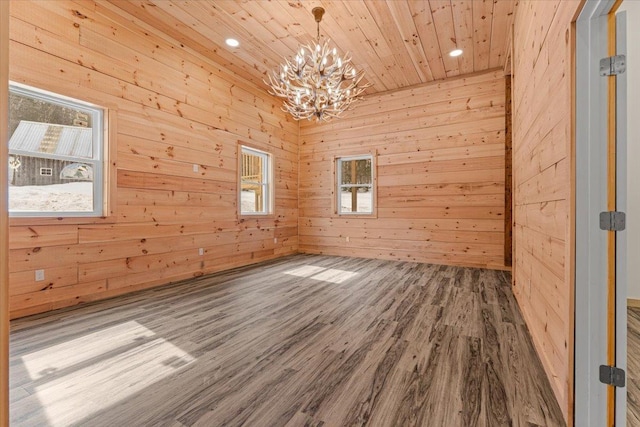empty room featuring wooden walls, wood finished floors, recessed lighting, wood ceiling, and a notable chandelier