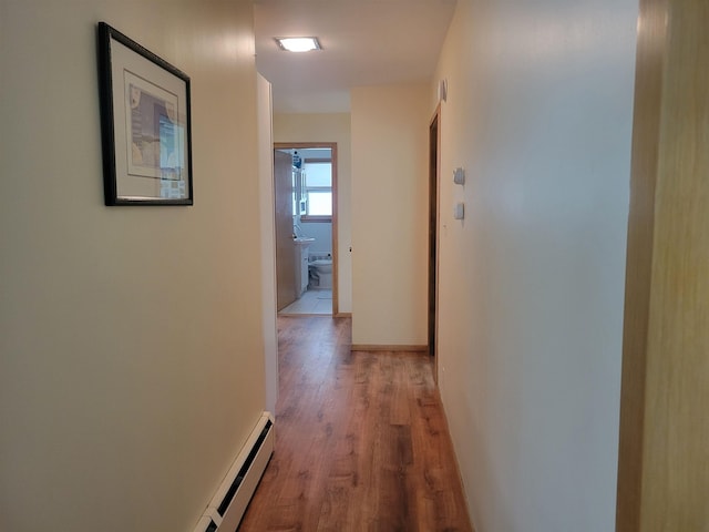 hallway featuring baseboards, light wood-type flooring, and a baseboard radiator