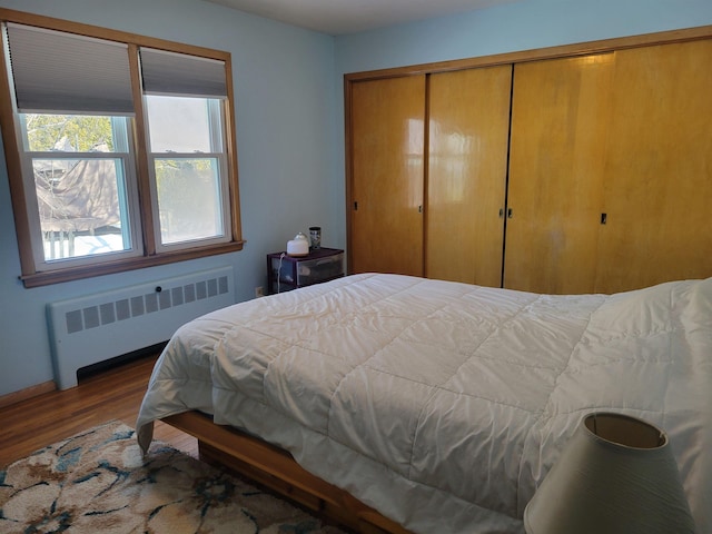 bedroom featuring a closet, radiator, and wood finished floors