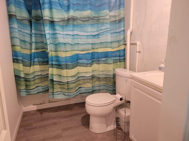 full bathroom with baseboards, toilet, wood finished floors, and vanity