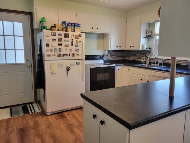 kitchen featuring white appliances, wood finished floors, a sink, dark countertops, and backsplash