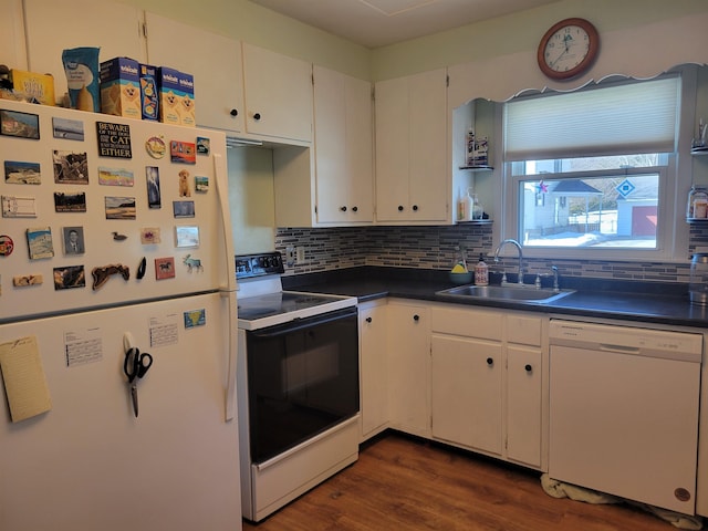 kitchen with white appliances, dark wood finished floors, a sink, decorative backsplash, and dark countertops