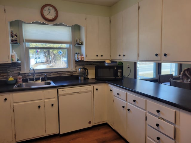 kitchen featuring dark countertops, a sink, black microwave, and white dishwasher