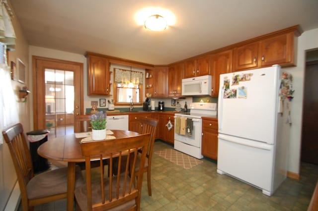 kitchen featuring white appliances, brown cabinets, and a sink