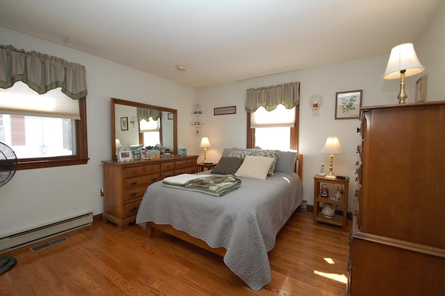 bedroom featuring visible vents, baseboard heating, and light wood-type flooring