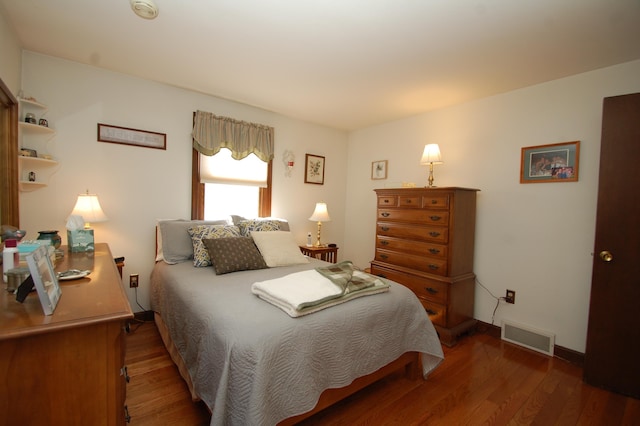 bedroom featuring visible vents, baseboards, and wood finished floors