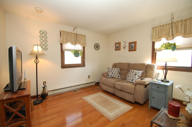 living area featuring a baseboard heating unit, light wood-style floors, and visible vents