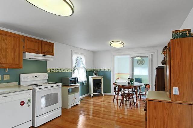 kitchen featuring under cabinet range hood, white appliances, light countertops, and light wood finished floors