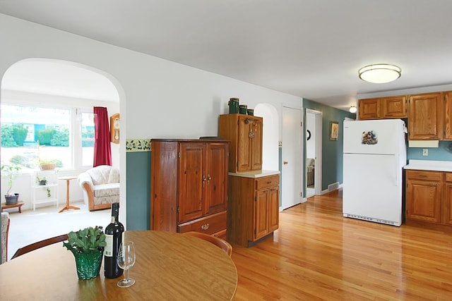 dining area with arched walkways and light wood finished floors