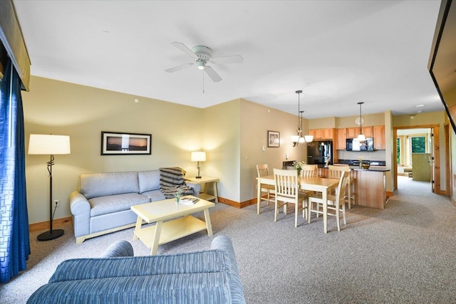 living room featuring light colored carpet, a ceiling fan, and baseboards