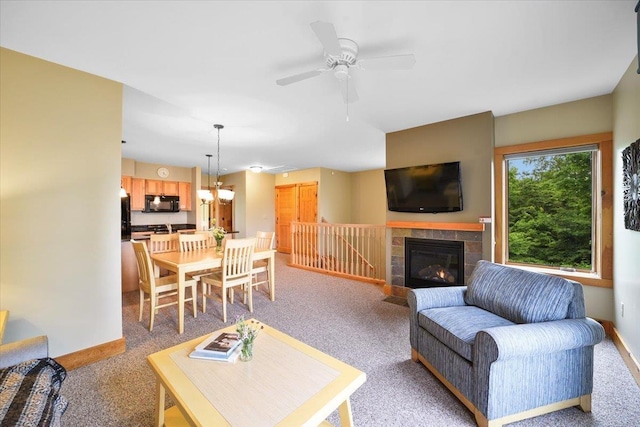 living room featuring a tiled fireplace, light colored carpet, baseboards, and ceiling fan