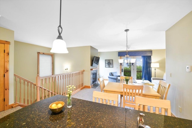 dining space featuring baseboards, a notable chandelier, and a glass covered fireplace